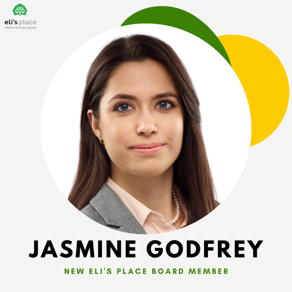 A headshot of a smiling woman with dark hair, set within a circular frame against a modern background. Below her photo, her name "JASMINE GODFREY" is displayed above the subtitle "NEW ELI'S PLACE BOARD MEMBER." The circle is accented with decorative green and yellow abstract leaf shapes, and the "eli's place" logo is visible in the top left corner.